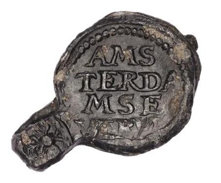 Sello de plomo con inscripción "AMSTERDAMSE" hallado en las excavaciones del metro de Ámsterdam.